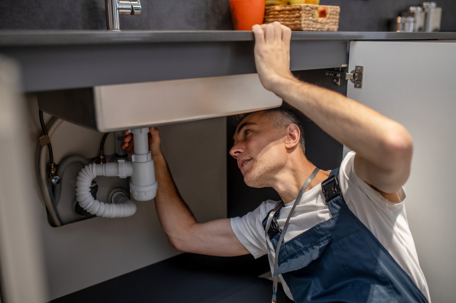 Man carefully examining bottom of sink and pipe